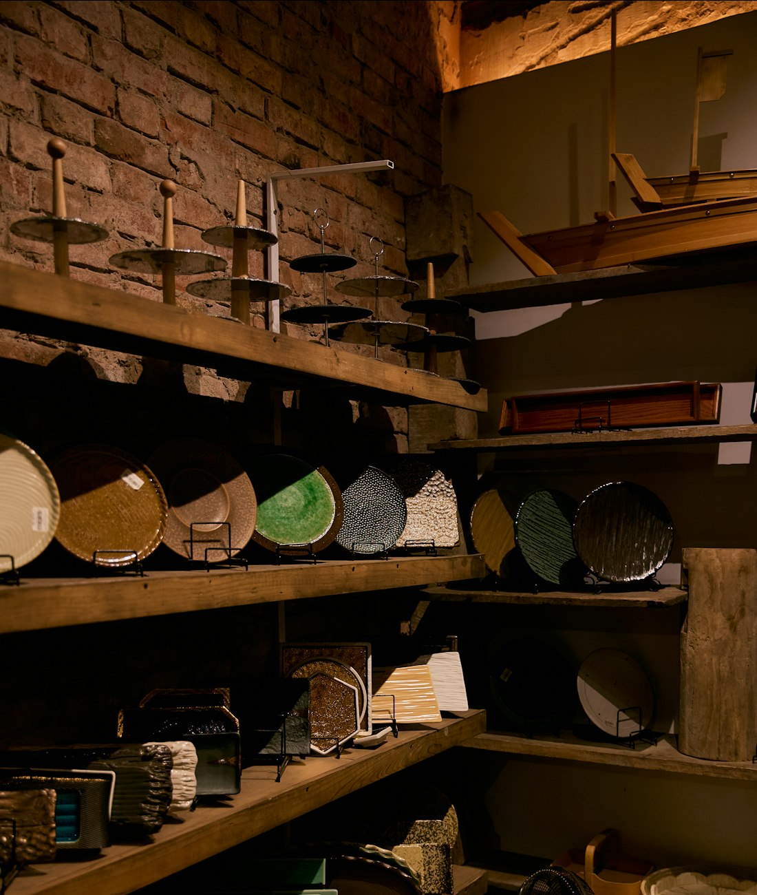 Bowls and boards on the wooden shelves by the brick wall